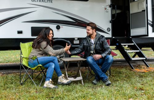 A couple is camping outside of an RV 