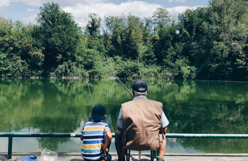 A family sitting near the water with fishing poles